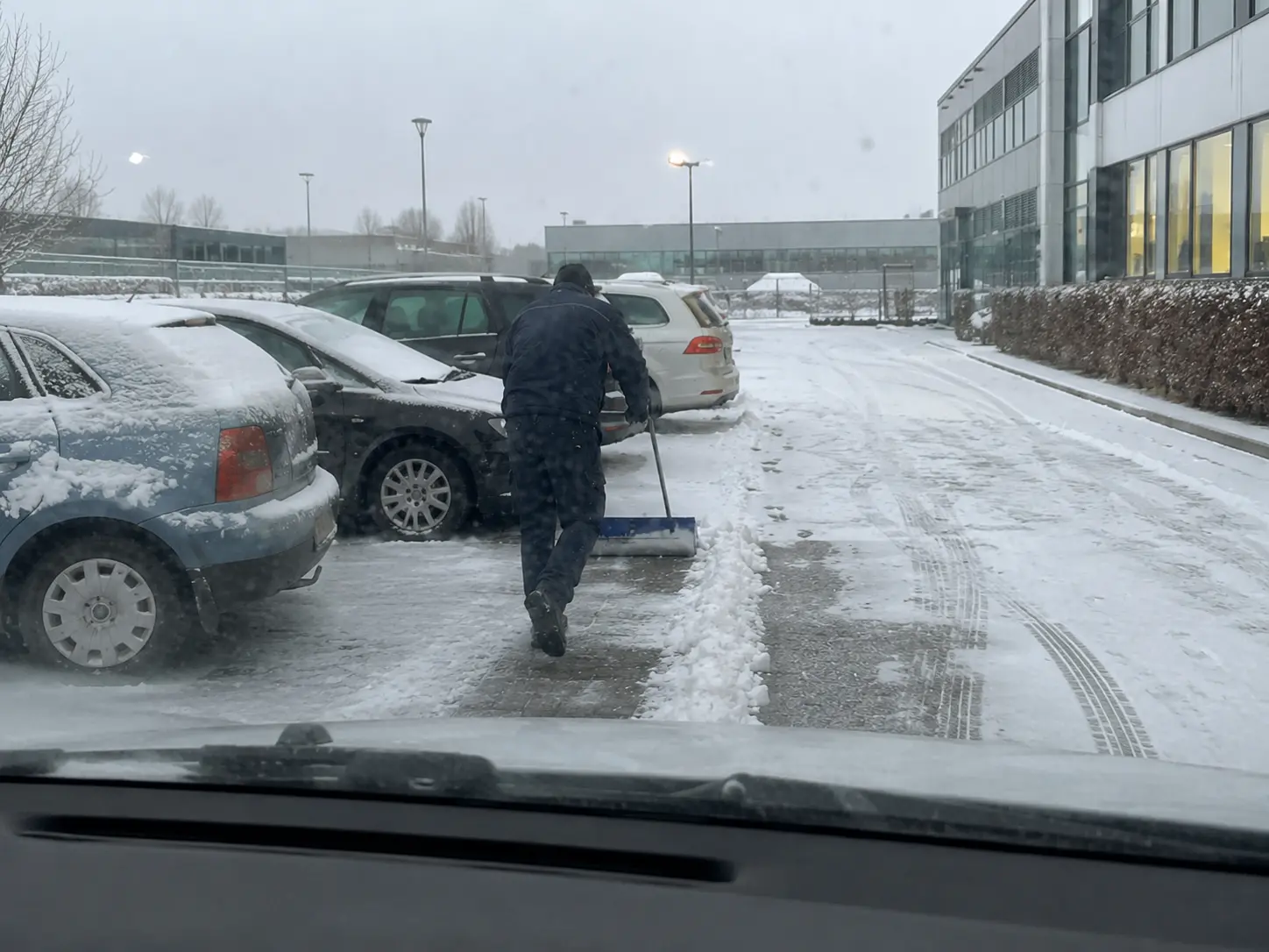 Winterdienst mit Schneeschieber auf einem Firmenparkplatz in Leipzig
